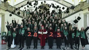 grupa absolwentów oraz władze agh stoja na schodach budynku A0 iw ykonują rzut bieterem trzymają napis Graduacja 2025