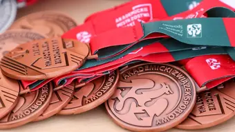Zdjęcie brązowych medali AZS nawleczonych na szarfy i leżących na stole