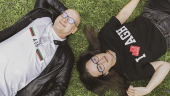 Meżczyzna i kobieta w koszulkach z logo AGH leżą na trawie